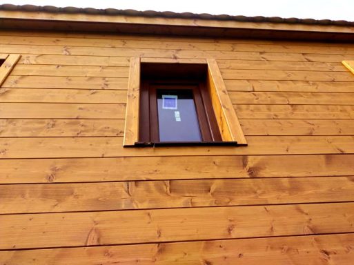 Ventana oscura en una pared de madera, situada en la parte superior.