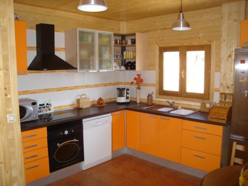 Cocina moderna con muebles naranjas y electrodomésticos en un ambiente acogedor.