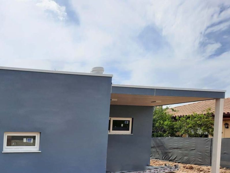 Casa moderna de color gris con un cielo nublado de fondo.