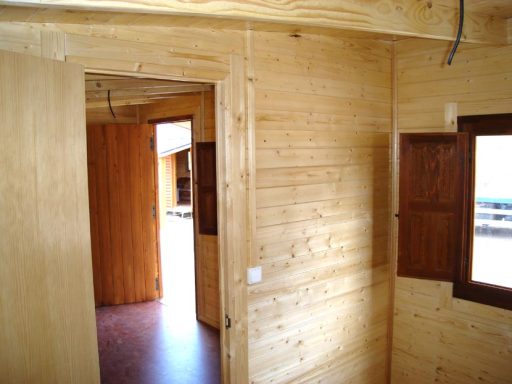 Interior de una casa de madera con puertas y ventanales iluminados.