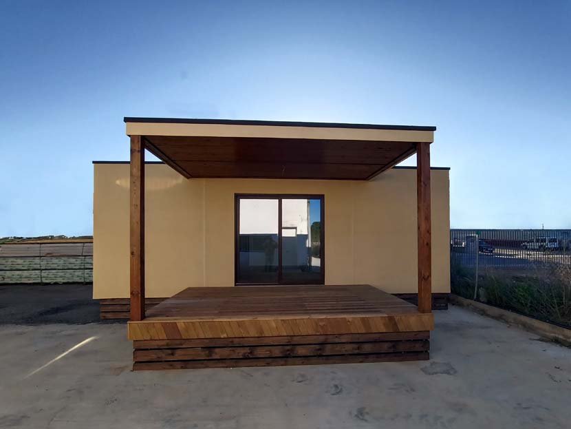Edificio moderno con un porche de madera y grandes ventanales. Fondo despejado.