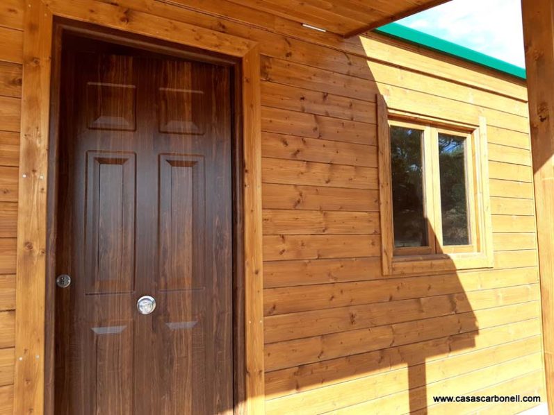 Puerta de madera y ventana en una pared de tablones de madera.
