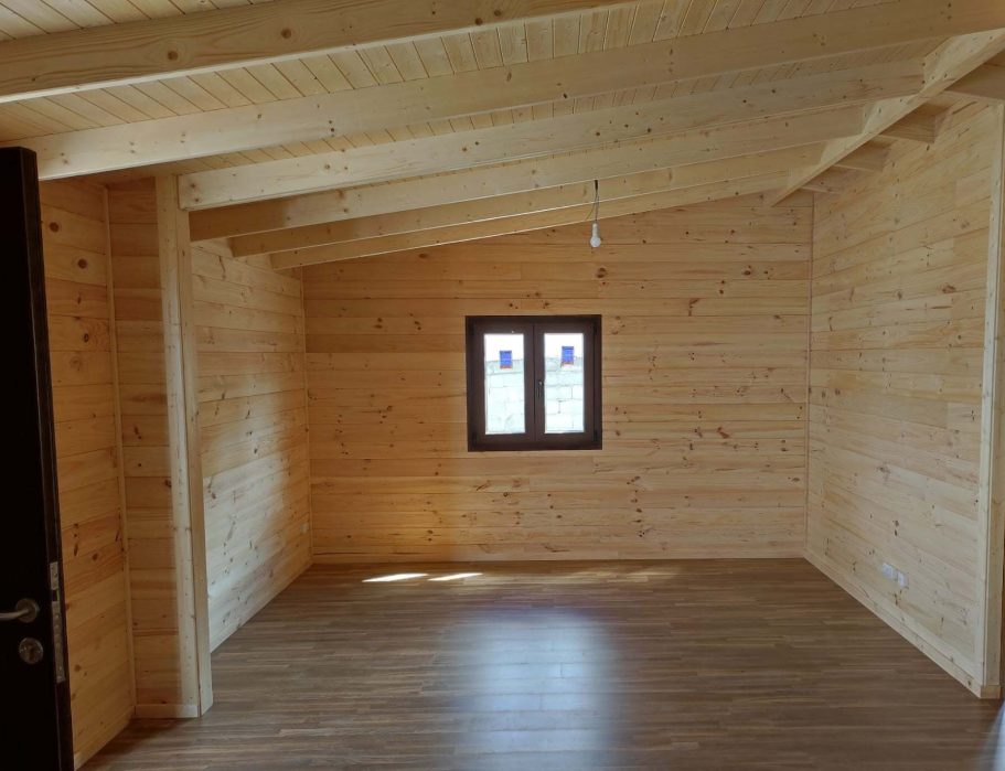 Interior vacío de una casa prefabricada de madera con paredes y techo de madera clara.