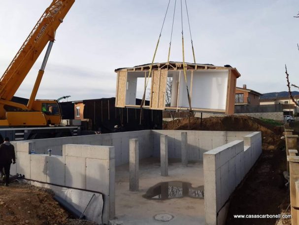 Base de casa prefabricada para conformar sótano con estructura de hormigón Grúa levantando una estructura de vivienda sobre una base de hormigón.