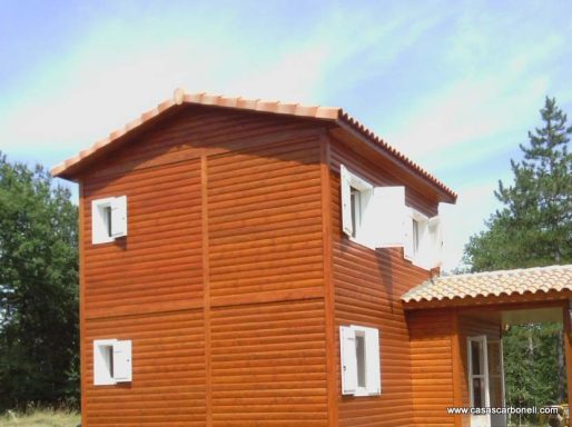 Casa prefabricada de madera de dos plantas con techo a dos aguas y ventanas blancas.