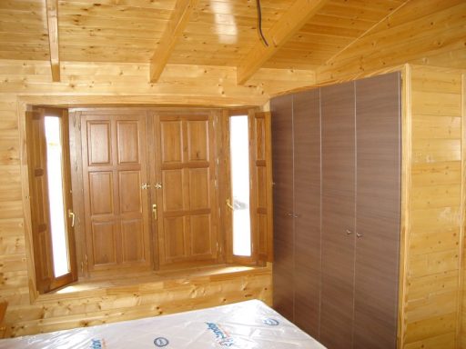 Interior de una cabaña de madera con una ventana y una pared de armario.