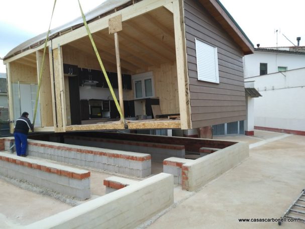 Base de muros corridos sobre losa de hormigón Casa en construcción elevada sobre una base, con estructuras de soporte visibles.