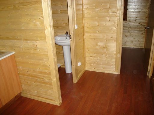 Baño con lavabo y puerta en un ambiente de madera con suelo de madera oscura.