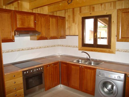 Cocina de madera con fregadero, horno y electrodomésticos, con ventana.