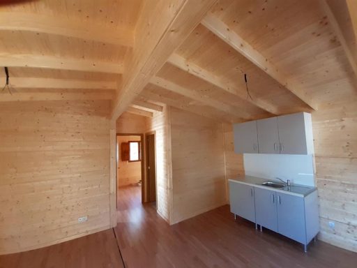 Interior de una casa de madera con techos altos y cocina sencilla.