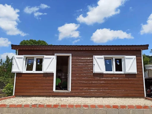 Casa prefabricada de madera con ventanas blancas y cielo azul con nubes.