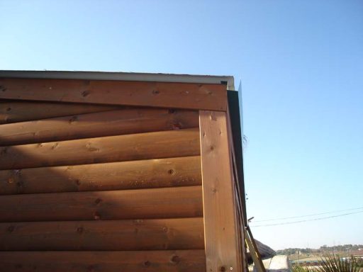 Parte superior de una pared de madera con un cielo despejado al fondo.