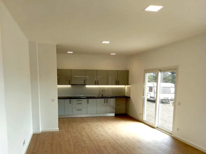 Sala de estar moderna con cocina integrada y grandes ventanales.