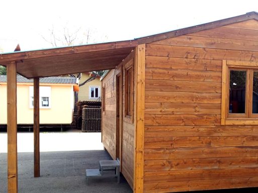 Casa de madera con techo a dos aguas y porche, situada en un entorno despejado.