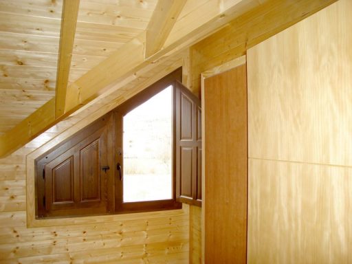 Interior de una habitación con pared de madera y ventanas pequeñas.