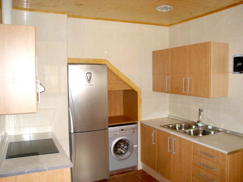 Cocina moderna con muebles de madera, electrodomésticos y espacio para lavadora.