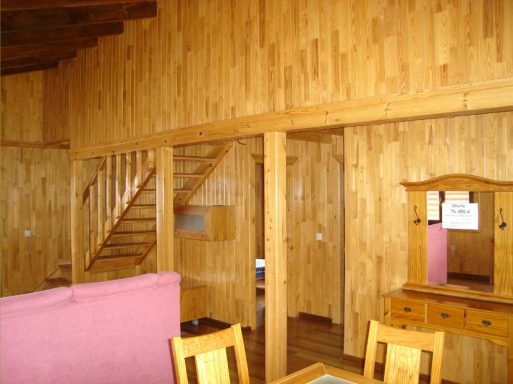 Interior de una casa prefabricada de madera con escaleras y muebles rústicos.