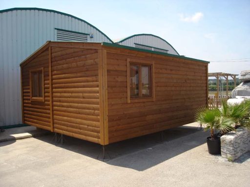 Casa de madera con ventanas, ubicada en un área al aire libre.