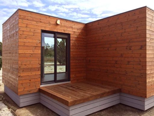 Casa prefabricada moderna de madera con terraza y grandes ventanales.