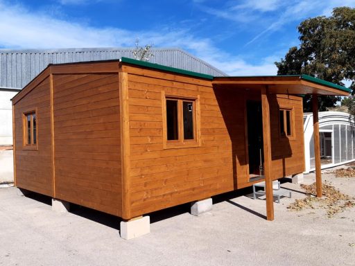 Casa de madera con ventanas y porche, ubicada en un entorno claro y soleado.