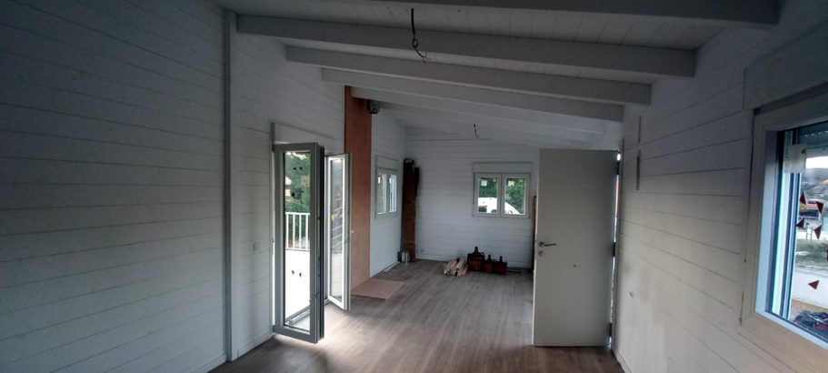 Interior de una habitación vacía con paredes blancas y suelo de madera.