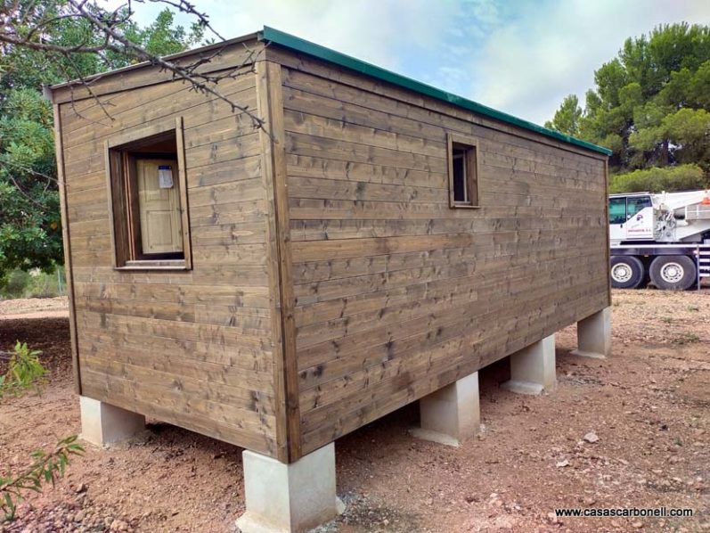 Construcción de una cabaña de madera sobre pilares, rodeada de vegetación.