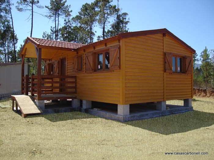 Casa de madera amarilla con porche, ventanas con contras y rampas para acceso.