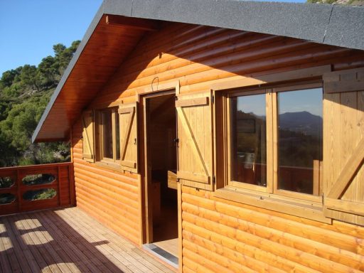 Casa prefabricada de madera con ventanas abiertas, situada en un entorno natural.