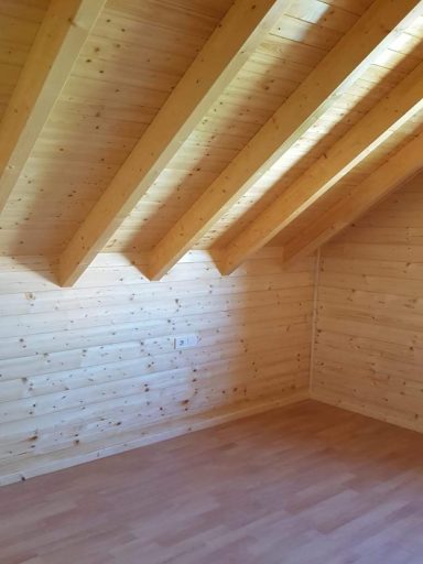 Interior de una habitación con paredes de madera y techos inclinados de vigas de madera.