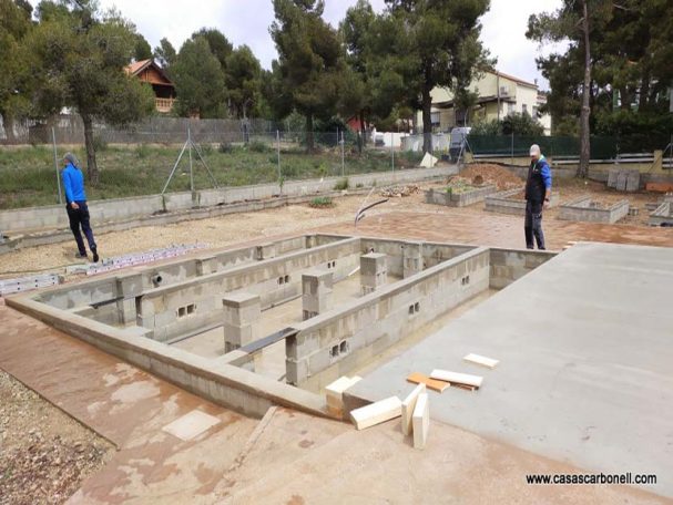 Base soterrada con muro corrido perimetral y pilares Obreros trabajando en una estructura de hormigón en una obra al aire libre.