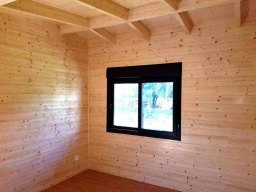 Interior de una habitación con paredes de madera y ventana con vista al exterior.