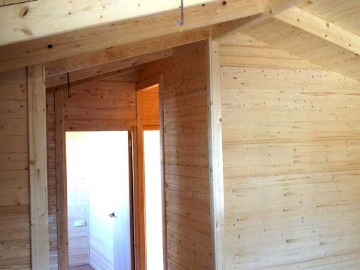 Interior de una habitación con paredes de madera clara y una puerta al fondo.