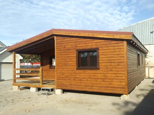 Casa prefabricada de madera con terraza, ventanas marrones y techo a dos aguas.