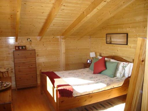 Dormitorio de estilo rústico con cama doble, paredes de madera y decoración acogedora.