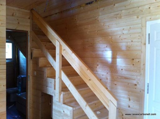 Escalera de madera con paredes de paneles de madera en un interior acogedor.