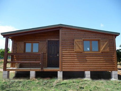 Casa prefabricada de madera de una planta con ventanas y puerta en un entorno rural.