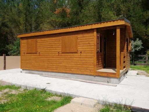 Casa prefabricada de madera con ventanas abatibles, ubicada en un entorno natural.