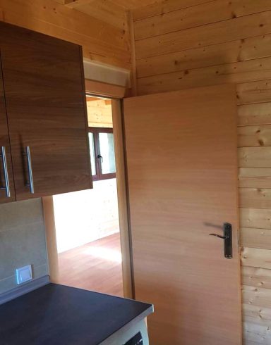 Cocina con muebles de madera y una puerta de madera que da a otra habitación.