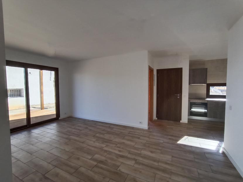 Espacio interior amplio y luminoso, con ventanas grandes y suelo de madera.