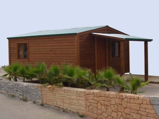 Casa de madera con techo a dos aguas y porche, rodeada de palmeras.