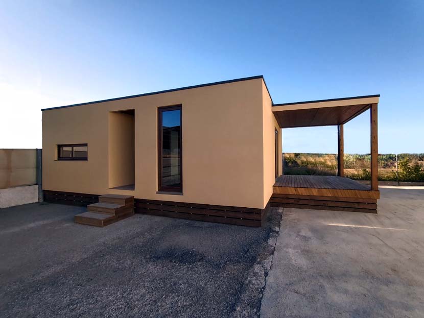 Fachada de una casa moderna con porche y entorno natural.