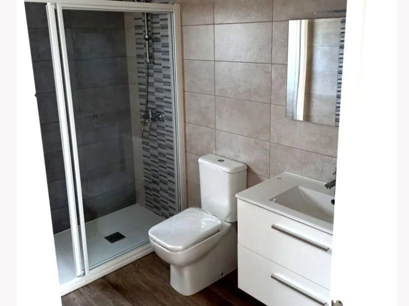 Baño moderno con ducha, inodoro y lavabo en un diseño minimalista.