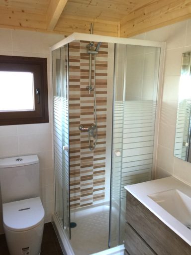 Baño moderno con ducha de cristal, inodoro y lavabo en tonos neutros.