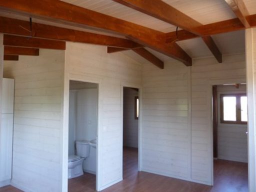 Interior de una habitación con techos de vigas de madera, con baño y ventanas.