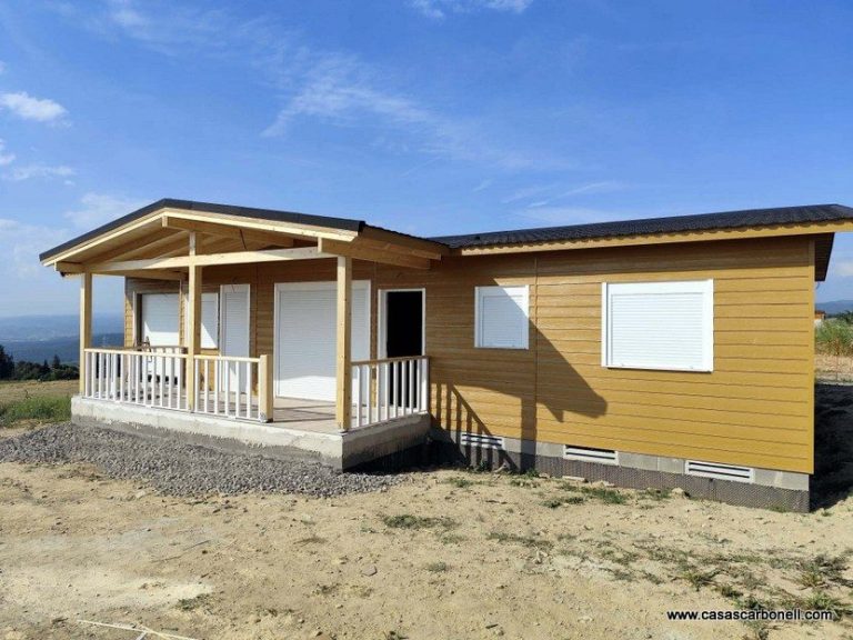Casa unifamiliar de color amarillo con porche y ventanas blancas en un paisaje rural.