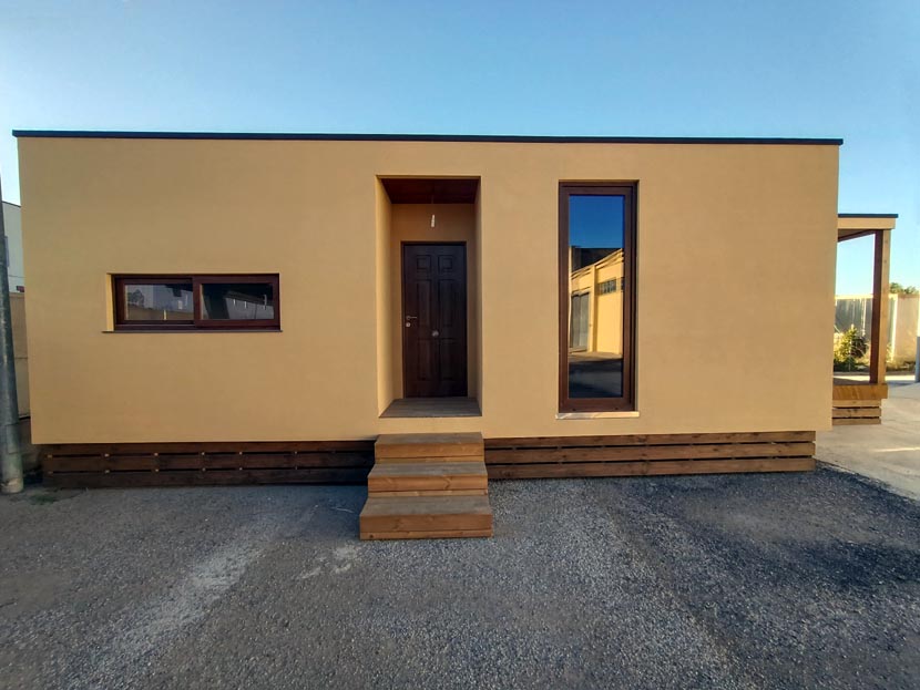 Casa unifamiliar de una sola planta con fachada amarilla y puerta de madera.