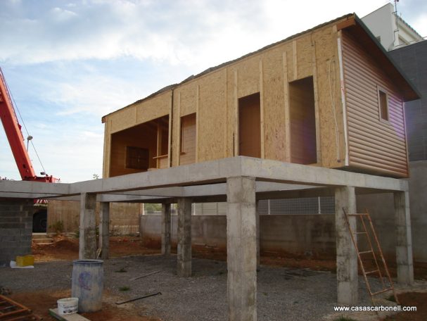 Base de hormigón elevada Construcción de una casa con estructura de concreto y paredes de madera en progreso.