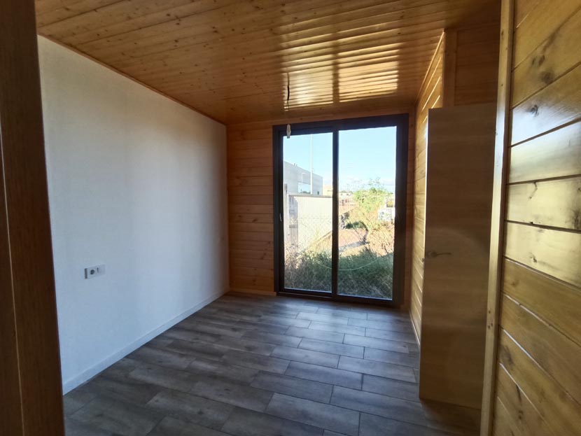 Interior de una habitación con paredes de madera y grandes ventanales.