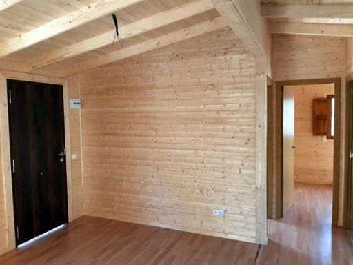 Interior de una cabaña de madera con paredes y techos de tablones y suelo laminado.