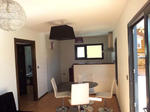 Interior de una vivienda moderna con mesa de comedor y cocina al fondo.